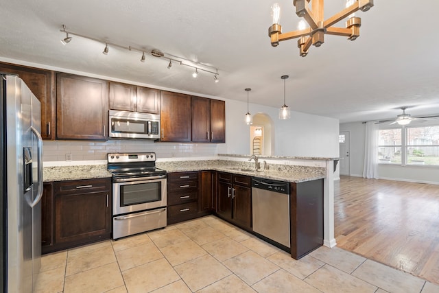 kitchen with ceiling fan with notable chandelier, sink, light hardwood / wood-style flooring, decorative light fixtures, and stainless steel appliances