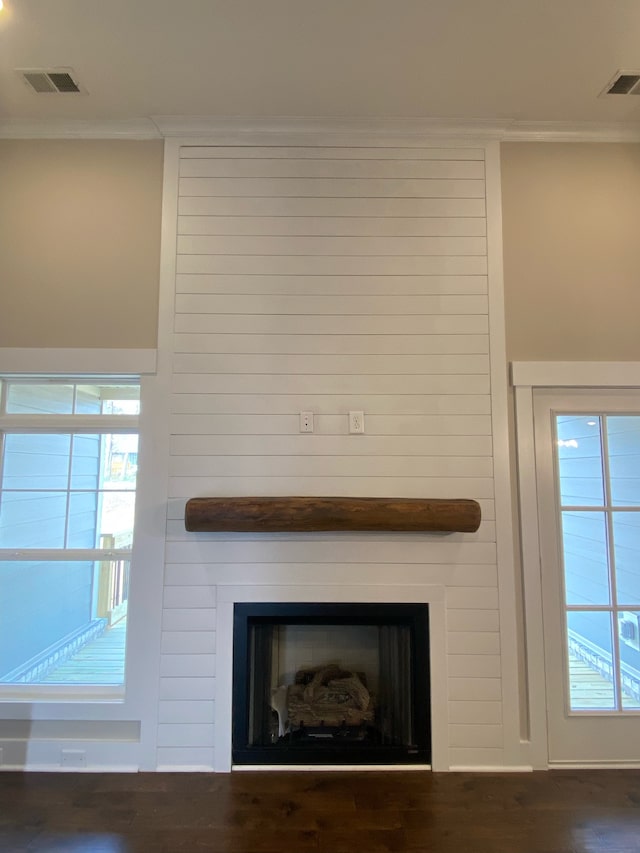 room details featuring wooden walls, a large fireplace, and wood-type flooring