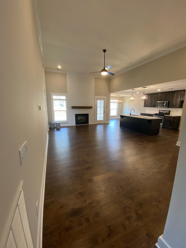 unfurnished living room with plenty of natural light, ceiling fan, dark hardwood / wood-style flooring, and a brick fireplace