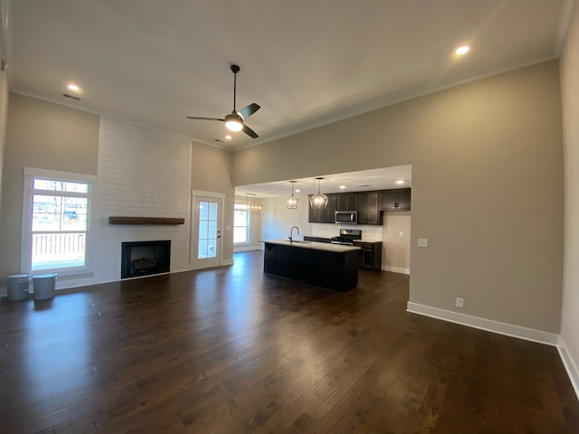 kitchen featuring sink, stainless steel appliances, dark hardwood / wood-style flooring, pendant lighting, and a center island with sink