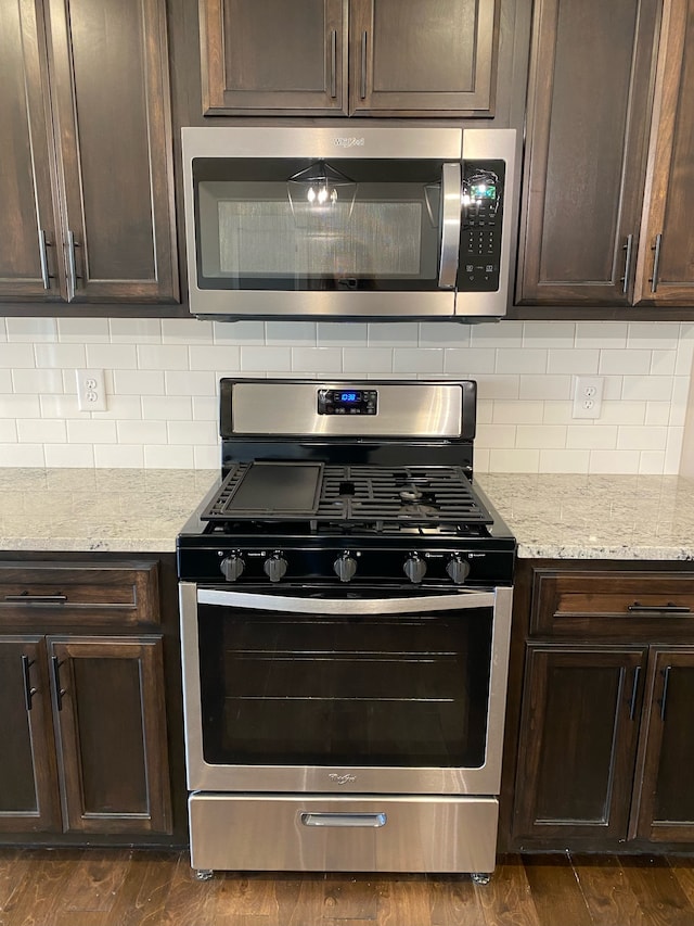 kitchen featuring dark brown cabinetry, dark wood-type flooring, and stainless steel appliances