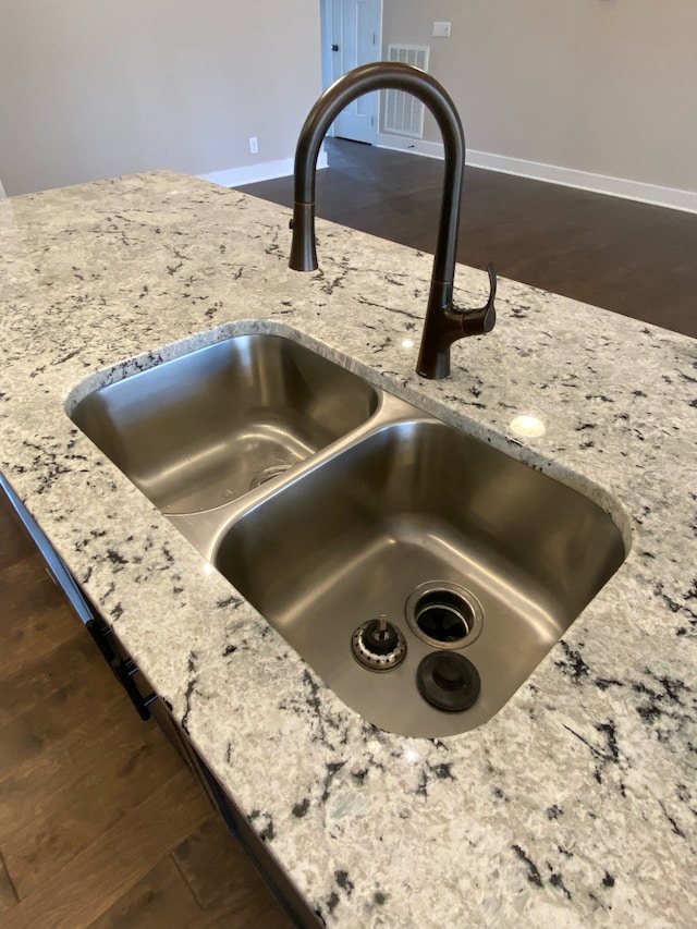 room details with light stone countertops, sink, and dark wood-type flooring