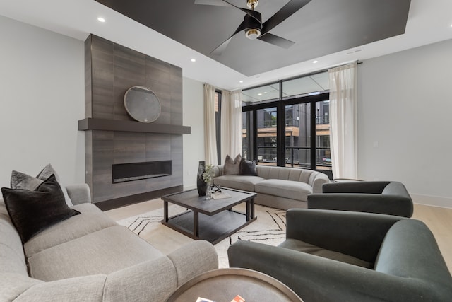 living room with a fireplace, light wood-type flooring, and ceiling fan