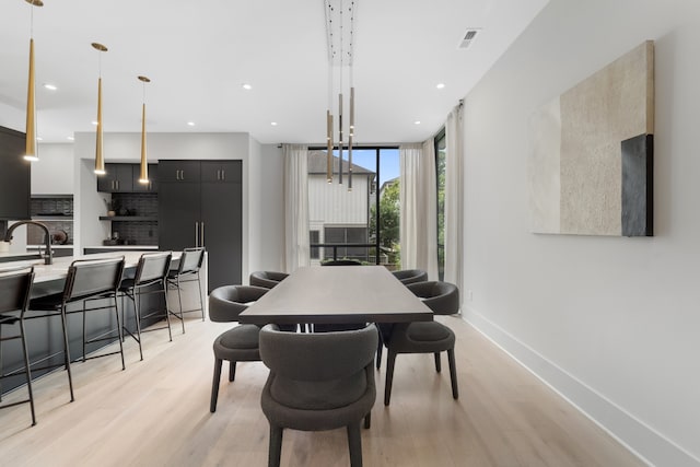 dining space with a wall of windows, light wood-type flooring, and sink