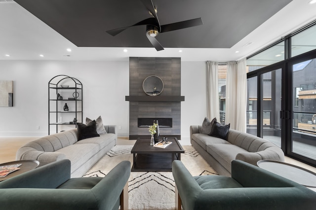 living room with ceiling fan, a fireplace, and light hardwood / wood-style flooring