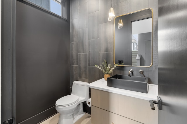 bathroom with vanity, toilet, tile walls, and a healthy amount of sunlight