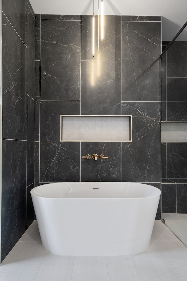 bathroom featuring a bath, tile patterned floors, and tile walls