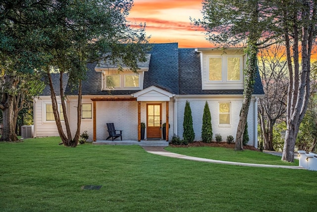 view of front of home with a yard and central AC unit