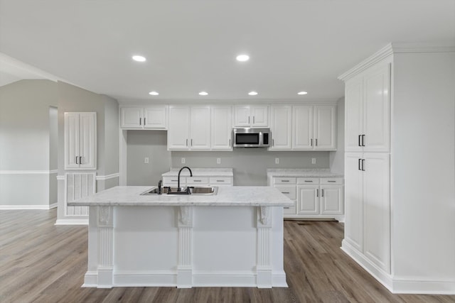 kitchen featuring light wood-type flooring, white cabinetry, sink, and a kitchen island with sink