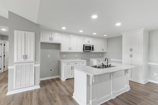 kitchen with light hardwood / wood-style flooring, an island with sink, white cabinetry, and sink