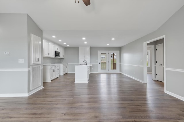 unfurnished living room with ceiling fan, dark wood-type flooring, and sink