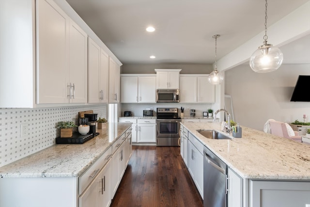 kitchen featuring hanging light fixtures, sink, dark hardwood / wood-style floors, appliances with stainless steel finishes, and white cabinetry