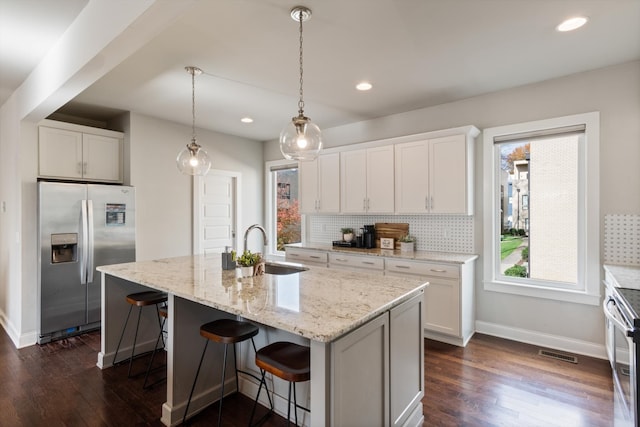 kitchen with a center island with sink, white cabinets, and appliances with stainless steel finishes