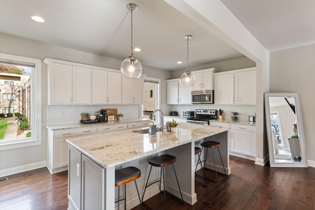 kitchen featuring white cabinetry, dark hardwood / wood-style flooring, an island with sink, and stainless steel appliances