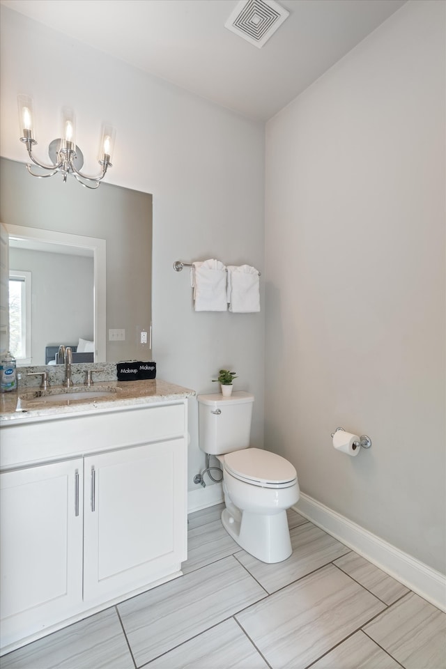 bathroom featuring toilet, vanity, and an inviting chandelier