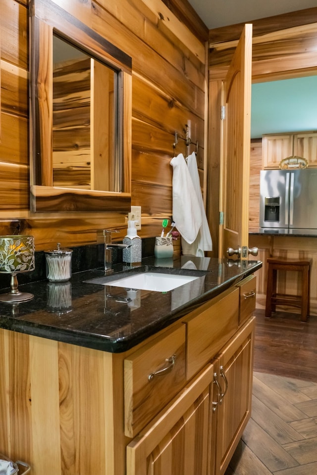 interior space with hardwood / wood-style floors, vanity, and wooden walls