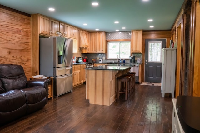 kitchen with wooden walls, a center island, dark wood-type flooring, and appliances with stainless steel finishes