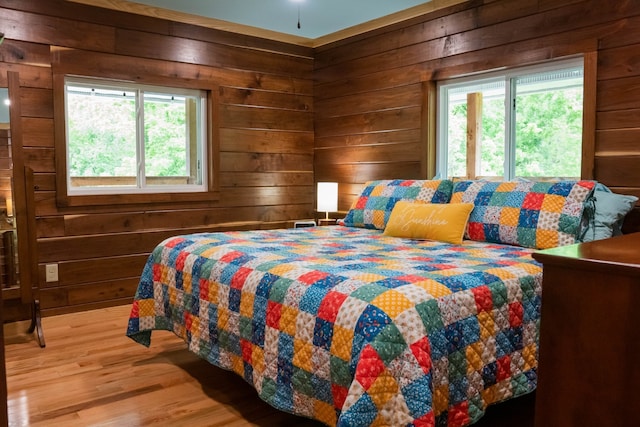 bedroom with multiple windows, wood walls, and wood-type flooring