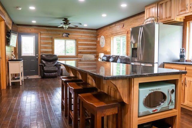 kitchen with a wealth of natural light, dark hardwood / wood-style flooring, log walls, and stainless steel appliances