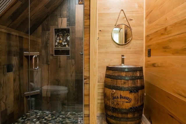 bathroom featuring lofted ceiling, wooden walls, vanity, and an enclosed shower