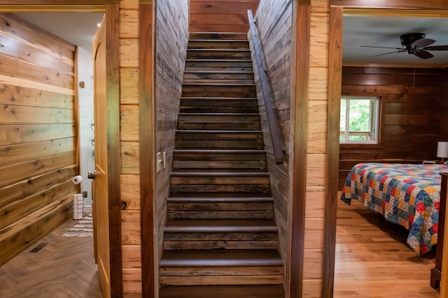 interior space with ceiling fan, light hardwood / wood-style floors, and wooden walls