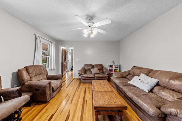 living room with hardwood / wood-style floors, ceiling fan, and a textured ceiling