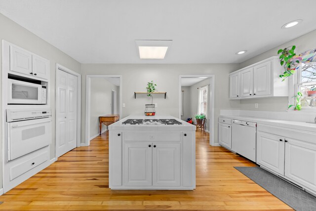 kitchen with white cabinets, white appliances, light hardwood / wood-style flooring, and sink