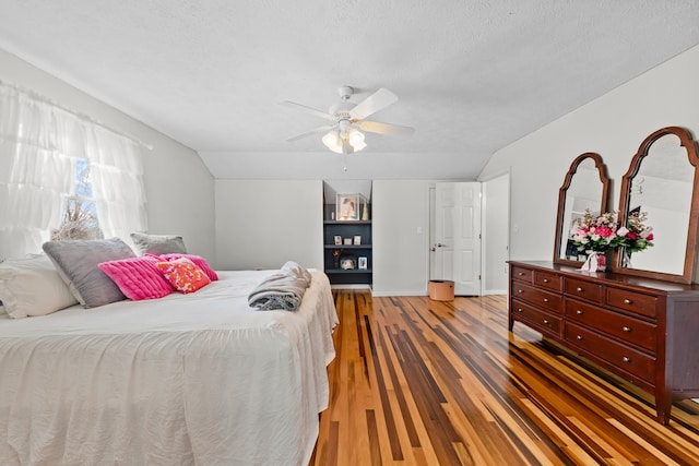 bedroom with hardwood / wood-style flooring, ceiling fan, lofted ceiling, and a textured ceiling