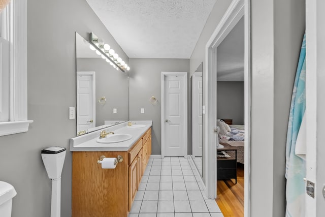 bathroom featuring tile patterned flooring, vanity, toilet, and a textured ceiling