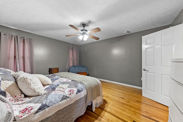 bedroom with ceiling fan, wood-type flooring, and a textured ceiling