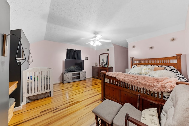 bedroom featuring a textured ceiling, ceiling fan, light hardwood / wood-style flooring, and vaulted ceiling