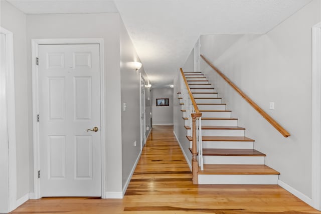 stairs with a textured ceiling and hardwood / wood-style flooring