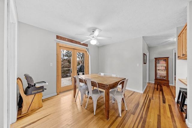 dining room featuring ceiling fan, light wood-type flooring, and a textured ceiling