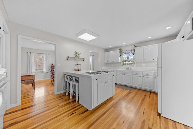 kitchen with white cabinets, light wood-type flooring, and white refrigerator