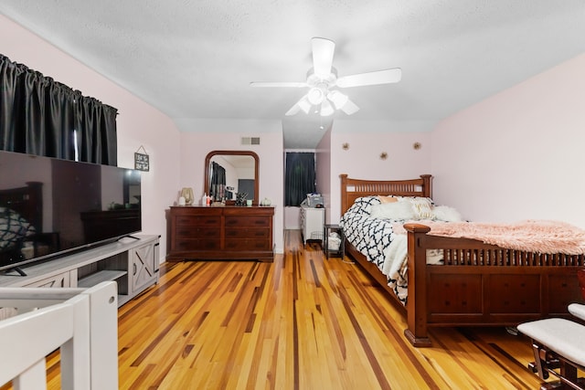 bedroom featuring ceiling fan, light wood-type flooring, and a textured ceiling