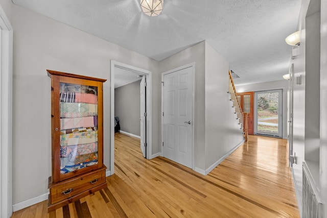 hallway with a textured ceiling and light wood-type flooring