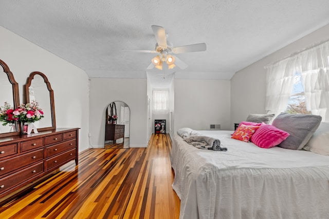 bedroom with multiple windows, ceiling fan, dark hardwood / wood-style flooring, and a textured ceiling