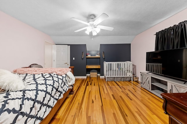 bedroom featuring hardwood / wood-style floors, a textured ceiling, ceiling fan, and lofted ceiling