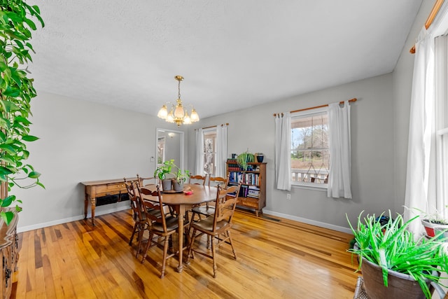 dining space featuring hardwood / wood-style floors, a textured ceiling, and a notable chandelier