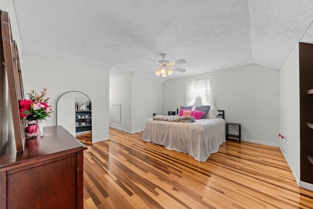 bedroom featuring a textured ceiling, ceiling fan, vaulted ceiling, and light wood-type flooring