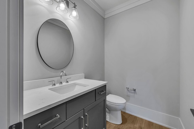 bathroom featuring crown molding, vanity, wood-type flooring, and toilet