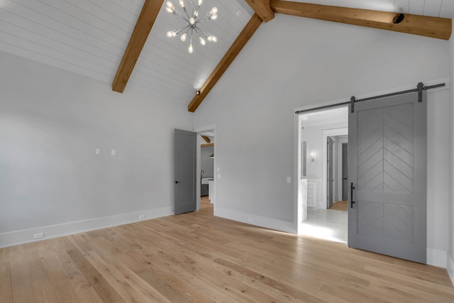 unfurnished living room featuring a barn door, beamed ceiling, high vaulted ceiling, and light wood-type flooring