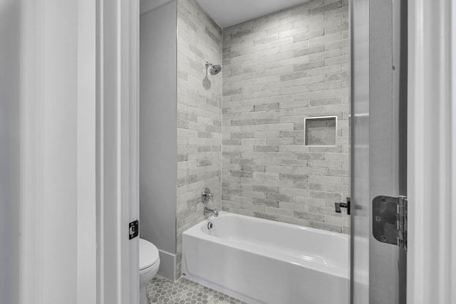 bathroom with tile patterned flooring, toilet, and tiled shower / bath