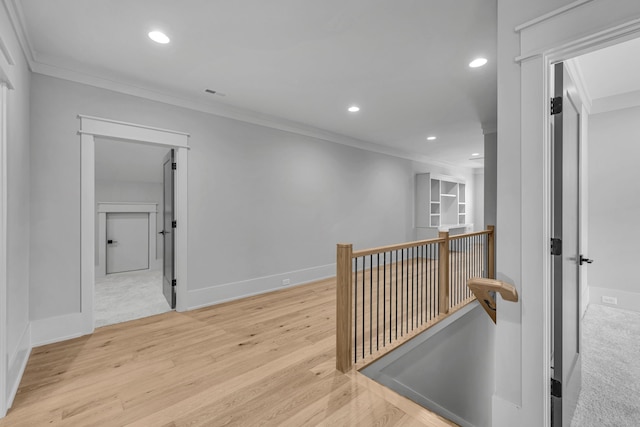 hallway with light wood-type flooring and ornamental molding