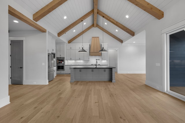 kitchen featuring a center island with sink, light hardwood / wood-style flooring, decorative light fixtures, beam ceiling, and white cabinetry