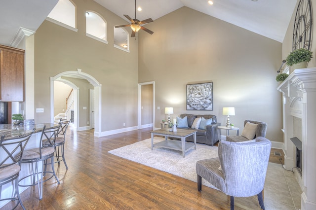 living room featuring hardwood / wood-style flooring, ceiling fan, and a towering ceiling