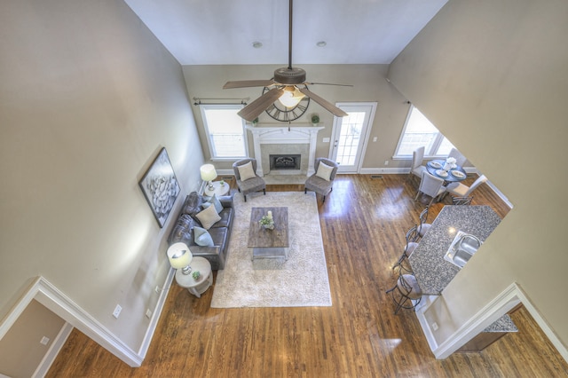 unfurnished living room with a wealth of natural light, a fireplace, ceiling fan, and dark wood-type flooring