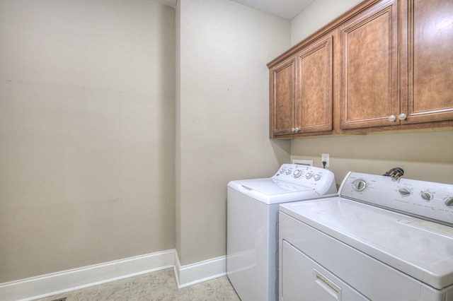 clothes washing area with cabinets and washer and clothes dryer