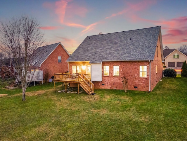 back house at dusk featuring a deck and a lawn