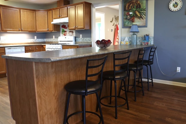 kitchen featuring white appliances, dark hardwood / wood-style flooring, and kitchen peninsula